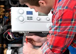 Tecnico che ripara una caldaia, indossa camicia a quadri rossa.