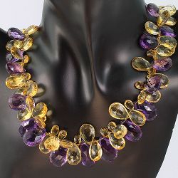 Necklace with purple and yellow gemstones displayed on a black mannequin bust.