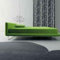 Grünes Sofa mit Kissen in modernem Raum mit Teppich und stilvoller Lampe im Hintergrund.
