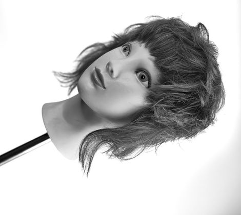 Testa di manichino con capelli ondulati corti, in bianco e nero.