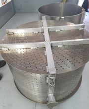 Contenedor cilíndrico metálico perforado en una superficie blanca.