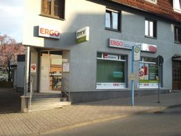 Gebäude mit ERGO- und DKV-Schildern, Bushaltestelle vorne, blauer Himmel im Hintergrund.