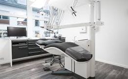 Modern dental office with chair, monitor, and equipment in a clean, bright setting.