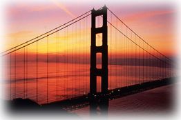 Hängebrücke bei Sonnenuntergang, reflektiert im Wasser, mit farbenprächtigem Himmel im Hintergrund.
