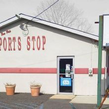 Small building labeled "Sports Stop" with pots outside and a visible glass door.