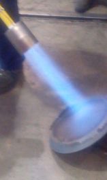 Torcia accesa con fiamma blu su superficie di metallo.