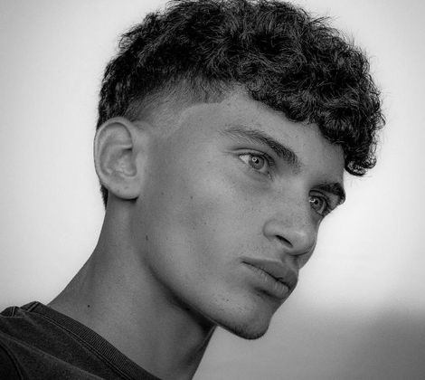 Giovane uomo di profilo con capelli ricci in bianco e nero.