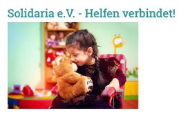 Mädchen im Rollstuhl umarmt Teddybär, Text: "Solidaria e.V. - Helfen verbindet!" im Hintergrund.