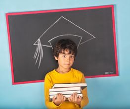 Niño con libros frente a una pizarra con dibujo de birrete de graduación. Fondo azul.