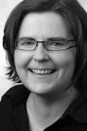 Ich kenne die Person nicht. Eine lächelnde Frau mit Brille in Schwarz-Weiß-Porträt.