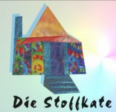 Buntes Haus mit kreativem Design, darunter steht "Die Stoffkate" geschrieben.