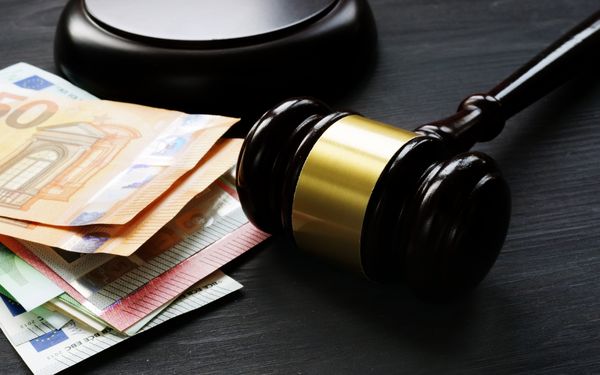 Ein Richterhammer liegt neben einem Stapel Geldscheinen, es symbolisiert den Einspruch gegen einen Bußgeldbescheid.