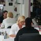 Zwei Frauen in einem Friseursalon, eine sitzt am Tisch, Spiegelbild im Hintergrund.