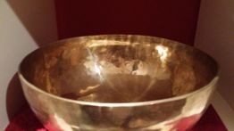 Goldene Metallschale auf rotem Hintergrund. Sie hat eine glatte, glänzende Oberfläche.