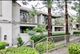 Apartment building with balconies, surrounded by trees and greenery on a cloudy day.