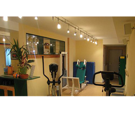 Kleines Fitnessstudio mit Geräten und dekorativen Pflanzen, hell erleuchtet.