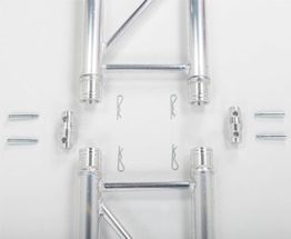 Metallteile und Verbindungselemente symmetrisch auf weißem Hintergrund angeordnet.