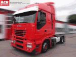 Roter Lkw mit Aufdruck "Stralis" steht auf einem Parkplatz, Gebäude im Hintergrund.