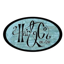 Oval logo with "Hair & Co on Ash" in elegant black script on a blue brick texture background.