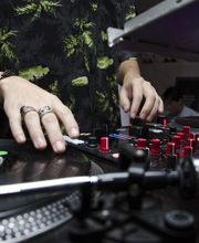 DJ mixa musica su una console con giradischi e mixer in un club.