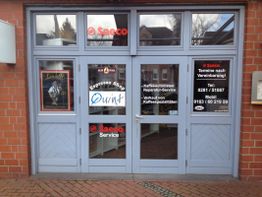 Geschäftseingang mit Werbeschildern für Kaffeemaschinen und Reparaturservice.