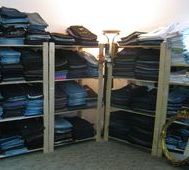 Regale mit gestapelten Jeans in einem Raum, beleuchtet von einer Lampe in der Mitte.