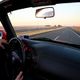Driving down an empty highway at sunset, view from inside the car.