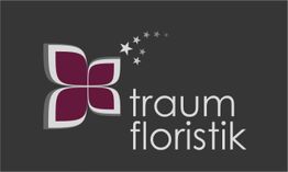 Logo mit stilisierter Blume und Text "traum floristik" auf dunklem Hintergrund.