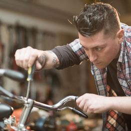 Person focusing intensely while fixing a bicycle handlebar with a screwdriver.