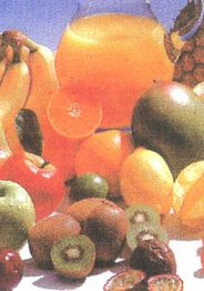 Verschiedene Früchte und ein Krug mit orangem Saft auf einem Tisch.