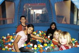 Kinder spielen in einem Bällebad mit bunten Bällen. Sie lachen und haben Spaß.