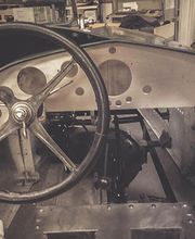 Altes Auto-Cockpit mit Lenkrad und Metallarmaturenbrett. Schrauben und Hebel sind sichtbar.