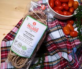 Pasta und Kirschtomaten auf kariertem Tuch, Packung "Palladio" sichtbar.