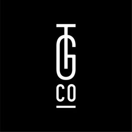 Schwarzes Logo mit weißem Text "TG CO" in vertikaler Anordnung auf schwarzem Hintergrund.