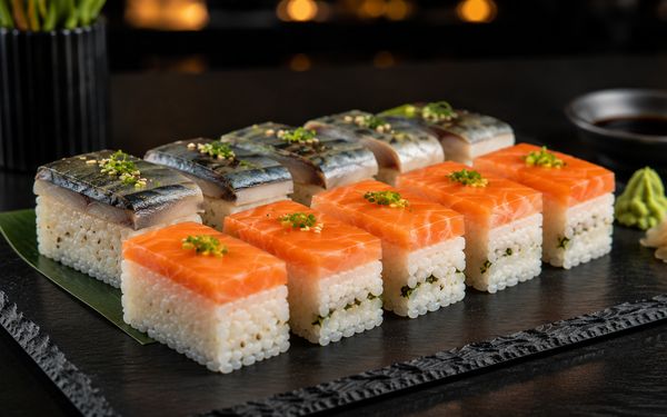 Verschiedene Arten an Oshi mit Lachs und Aal, serviert auf einer Schieferplatte.
