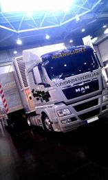 Weißer MAN-Lkw mit Aufschrift "Klanglight" in einer Halle, umgeben von industrieller Architektur.