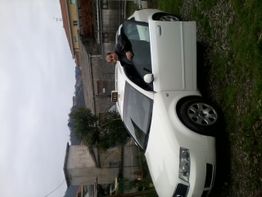 Uomo vicino a un'auto bianca in una zona residenziale. Tempo nuvoloso.