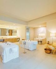 Sala de spa con dos camas de masaje, decoración luminosa y muebles acogedores.