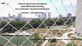 Rede de proteção em varanda com vista para quadra e cidade ao fundo. Texto sobre segurança.