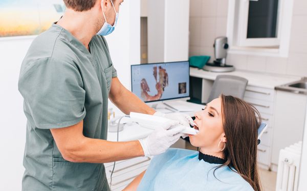 Ein Zahnarzt scannt die Zähne einer jungen Patientin mit einem 3d Scanner.