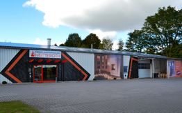 Außenansicht eines Geschäftsgebäudes mit großem Schaufenster und Werbeaufdruck „Hutteroth“.