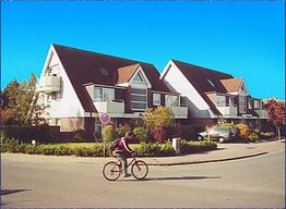 Radfahrer vor modernen Einfamilienhäusern bei blauem Himmel.