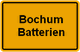 Gelbes Straßenschild mit der Aufschrift "Bochum Batterien" in schwarzer Schrift.