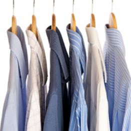 Several dress shirts on hangers, featuring various shades of blue and patterns.
