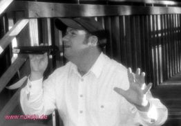 Eine Person mit Mikrofon singt auf einer Holztreppe.