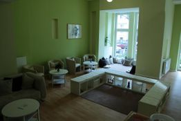 Heller Raum mit grünen Wänden, Sitzbereich aus Sofas und Stühlen und großem Fenster.