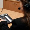 Woman with a headset using a conference call phone at a wooden desk.