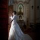 Sposa in abito bianco di fronte a una porta aperta in una chiesa.