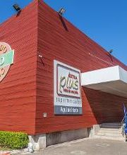 Fachada de um prédio comercial de madeira marrom com logotipos e céu azul ao fundo.