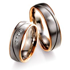 Zwei Eheringe mit silbernem Band und goldenen Kanten, einer mit kleinen Diamanten.